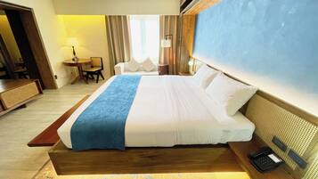 Une chambre d’hôtel avec un grand lit, des tables de chevet, un bureau et une chaise.