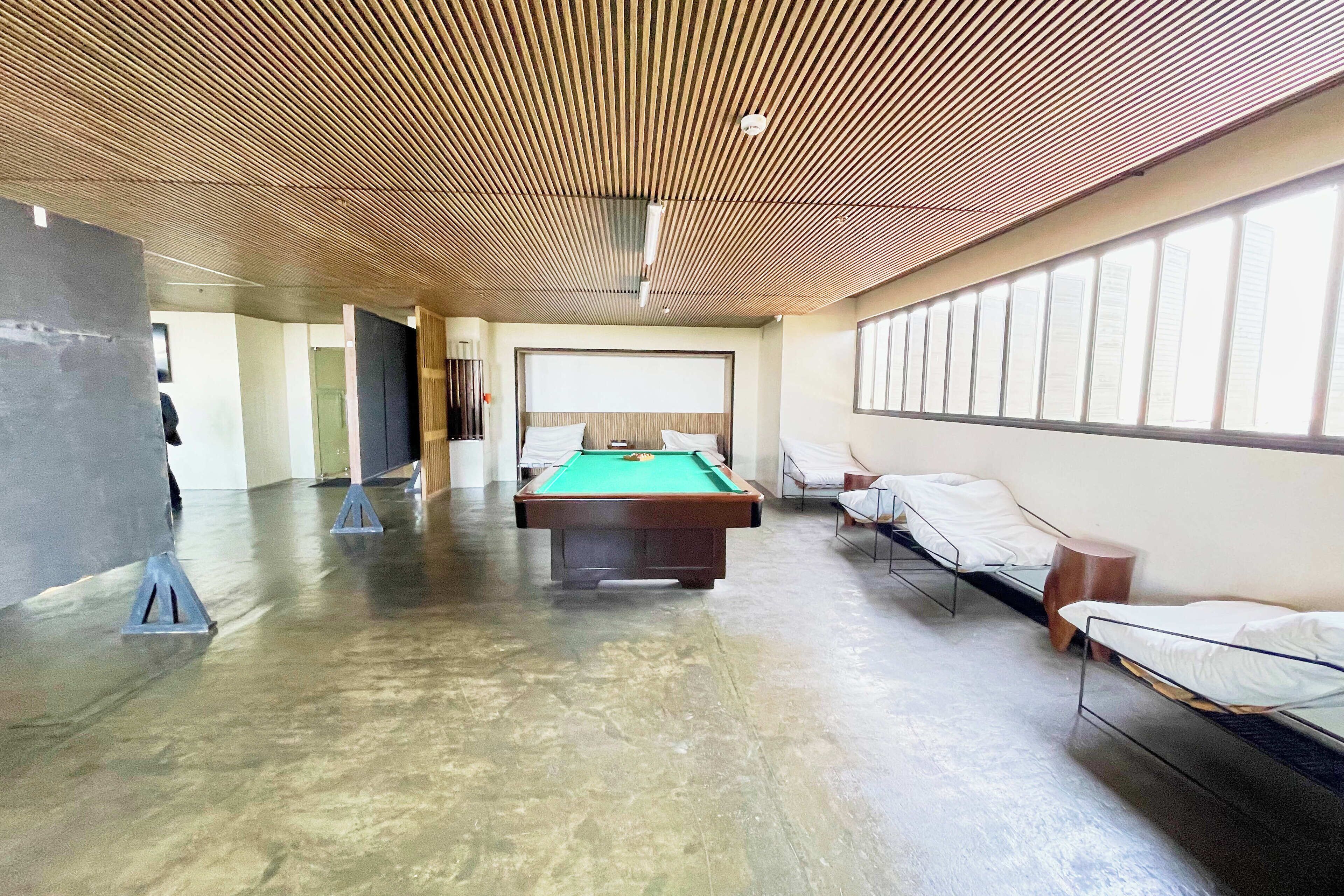 A spacious room with a pool table, bunk beds, and large windows.