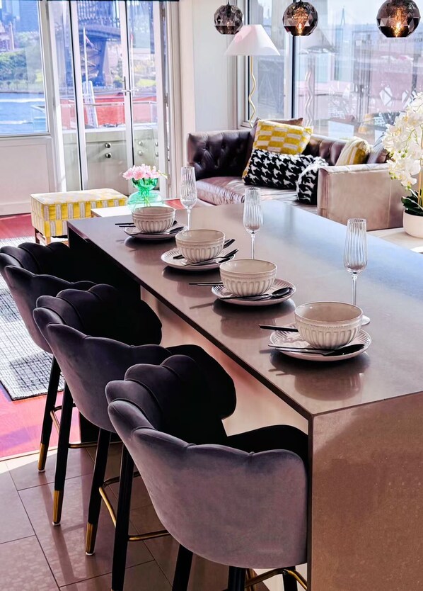 A modern dining area with a long table set for six, surrounded by dark chairs.