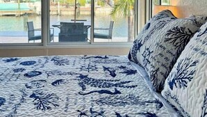A bedroom with a large window overlooking a pool and thatched-roof building. - Luxury Oceanfront 3BR with Pool, Dock & Boat Lift (Cortez)