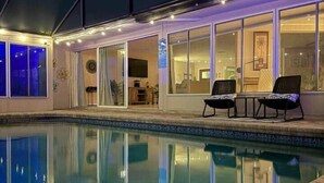An indoor swimming pool with clear water, surrounded by a covered patio area with two lounge chairs. - Luxury Oceanfront 3BR with Pool, Dock & Boat Lift (Cortez)