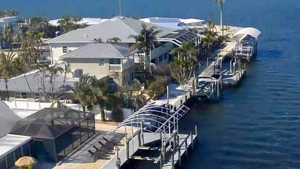 A waterfront property with a dock, houses, and palm trees. - Luxury Oceanfront 3BR with Pool, Dock & Boat Lift (Cortez)