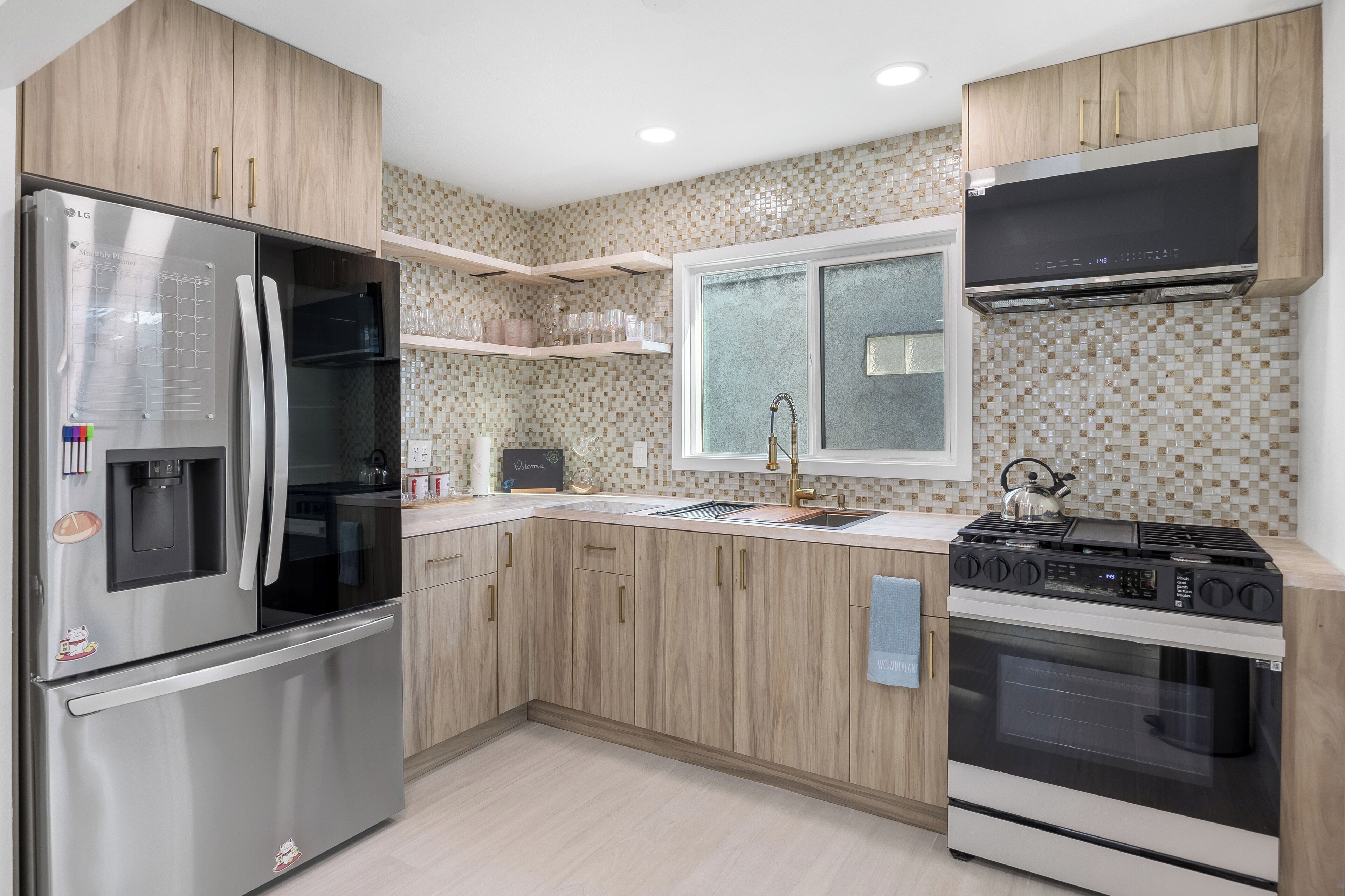 Une cuisine moderne avec des meubles en bois, des appareils électroménagers en acier inoxydable et un dosseret carrelé.