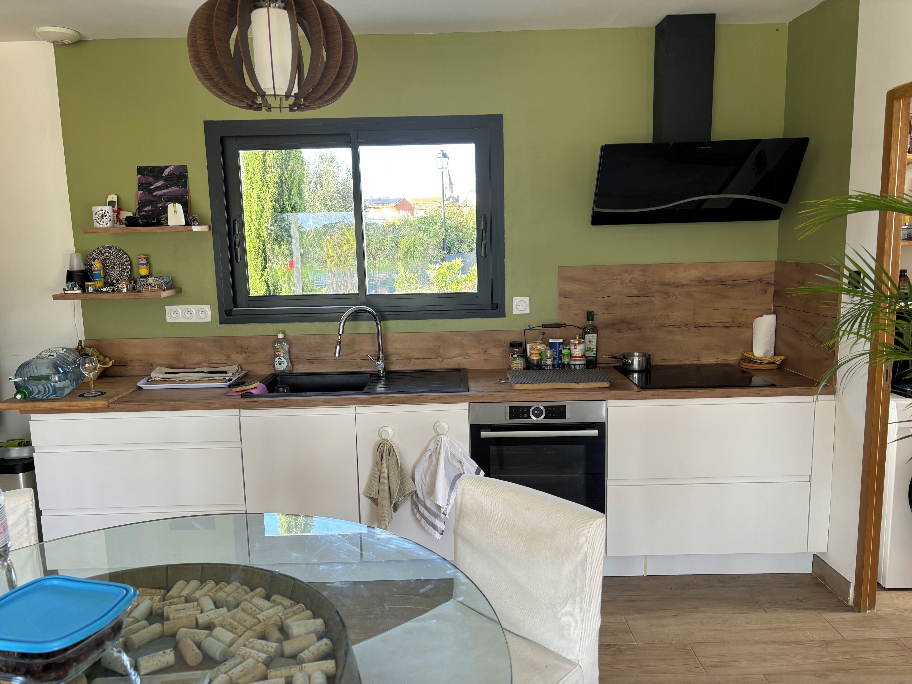 A modern kitchen with a large window, a built-in oven, and a sink.