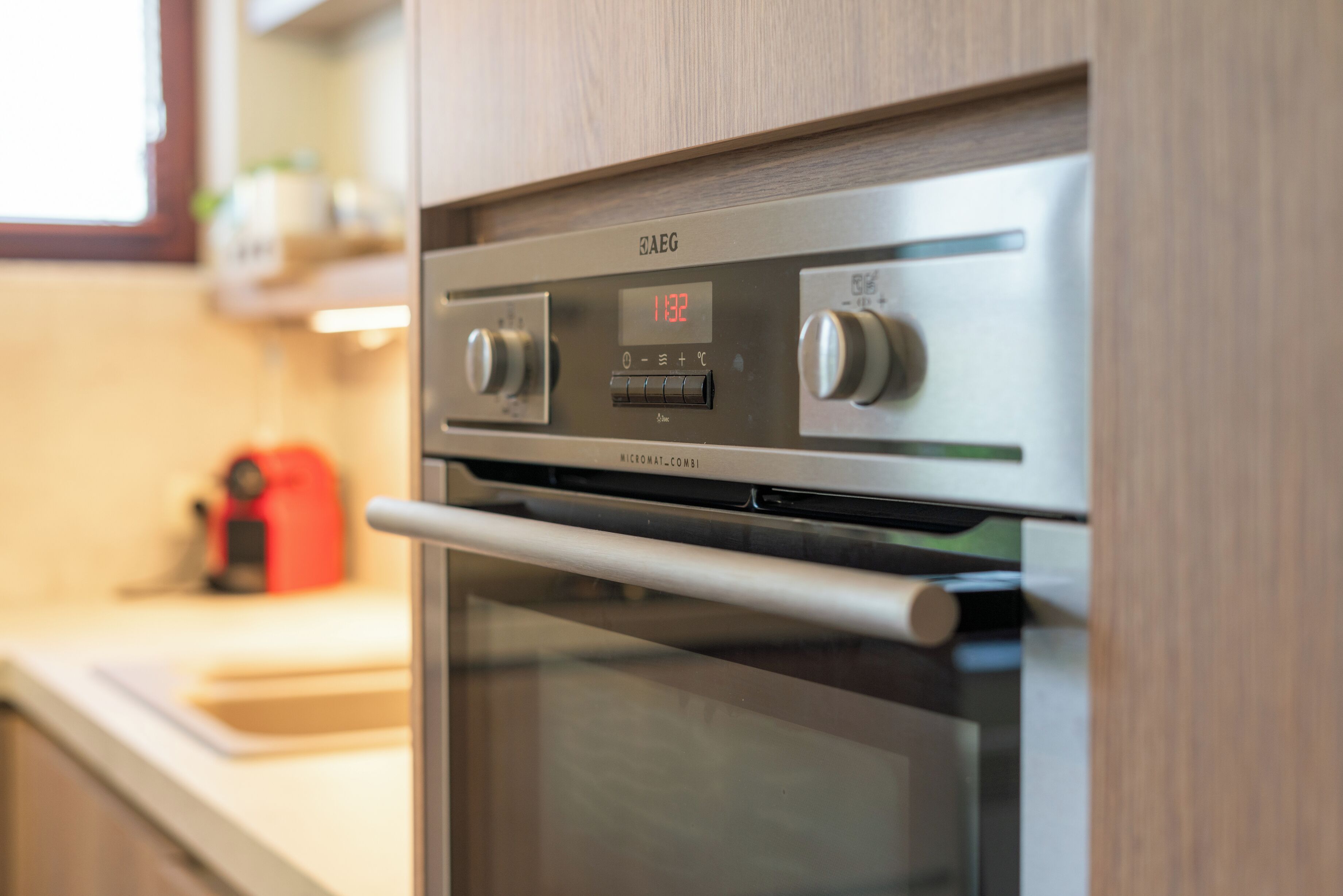 A kitchen with a stainless steel oven and a digital clock displaying 11:32.