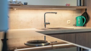 Eine moderne Küche mit einem Edelstahlarmaturen, einem grünen Wasserkocher und einem eingebauten Herd.