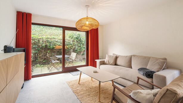 Ein modernes Wohnzimmer mit einer Couch, einem Couchtisch und einem Fernseher auf einer Holzkommode.