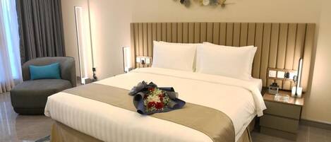 A hotel room with a large bed, a bedside table with a lamp, a chair, and a decorative wall piece.