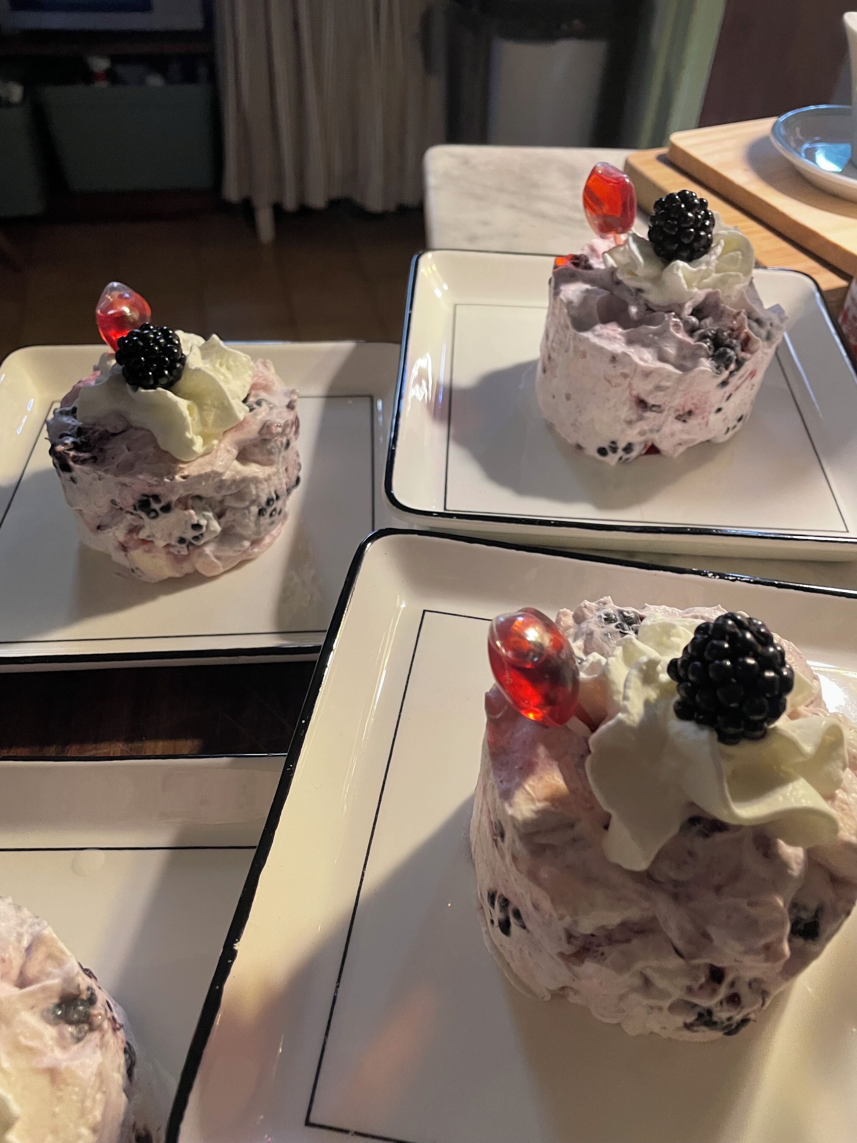 Three dessert cups on white plates with a marble pattern.
