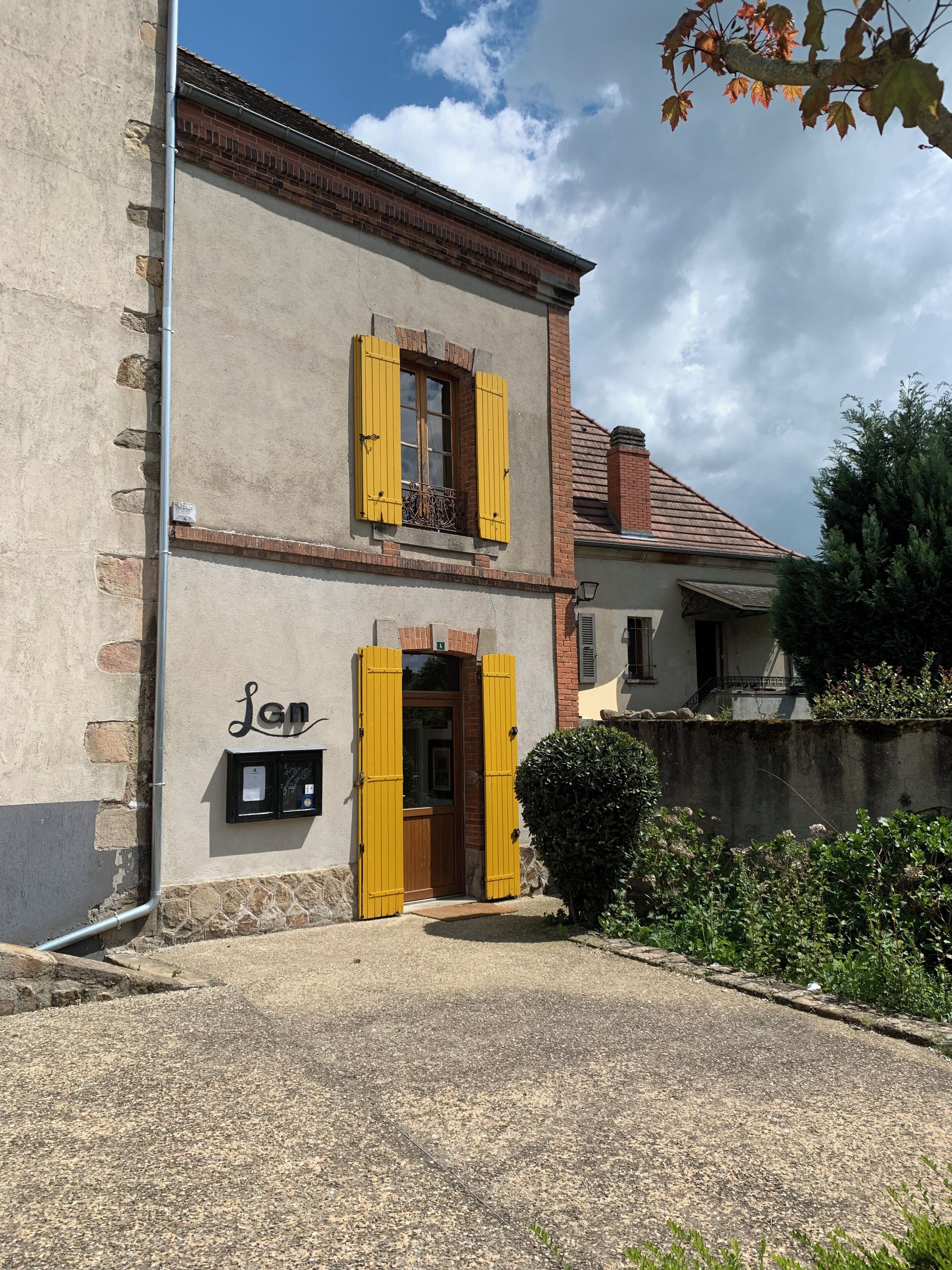 A two-story building with yellow shutters, a stone facade, and a small balcony.