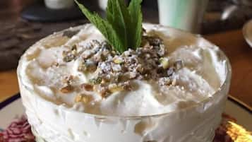 Un tazón de postre cremoso con nueces y una hoja de menta como adorno, servido en un plato con estampado floral.