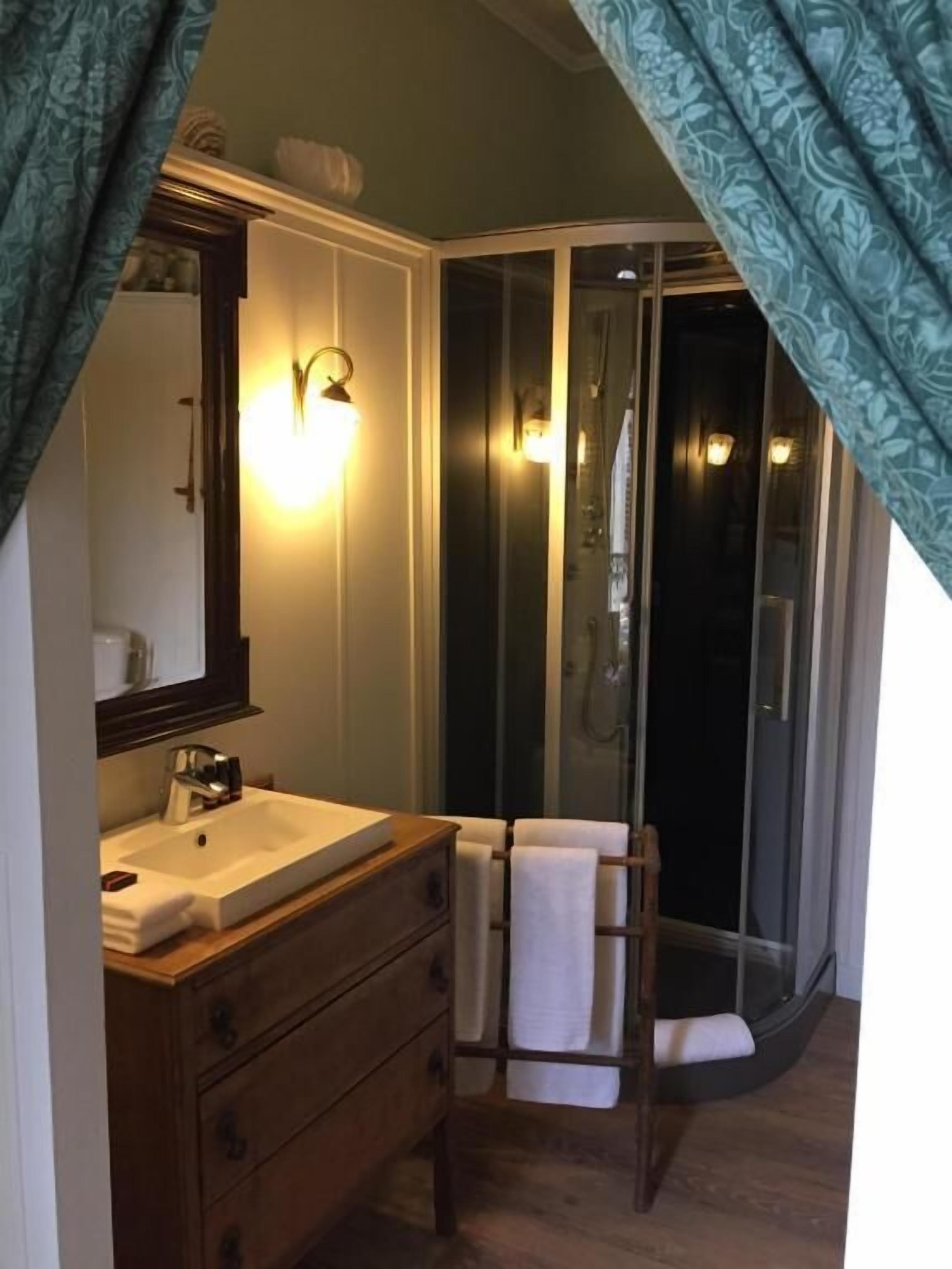 A bathroom with a wooden vanity, a mirror, a sink, and a shower with glass doors.