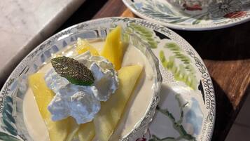 Two bowls of dessert with fruit and whipped cream on decorative plates.