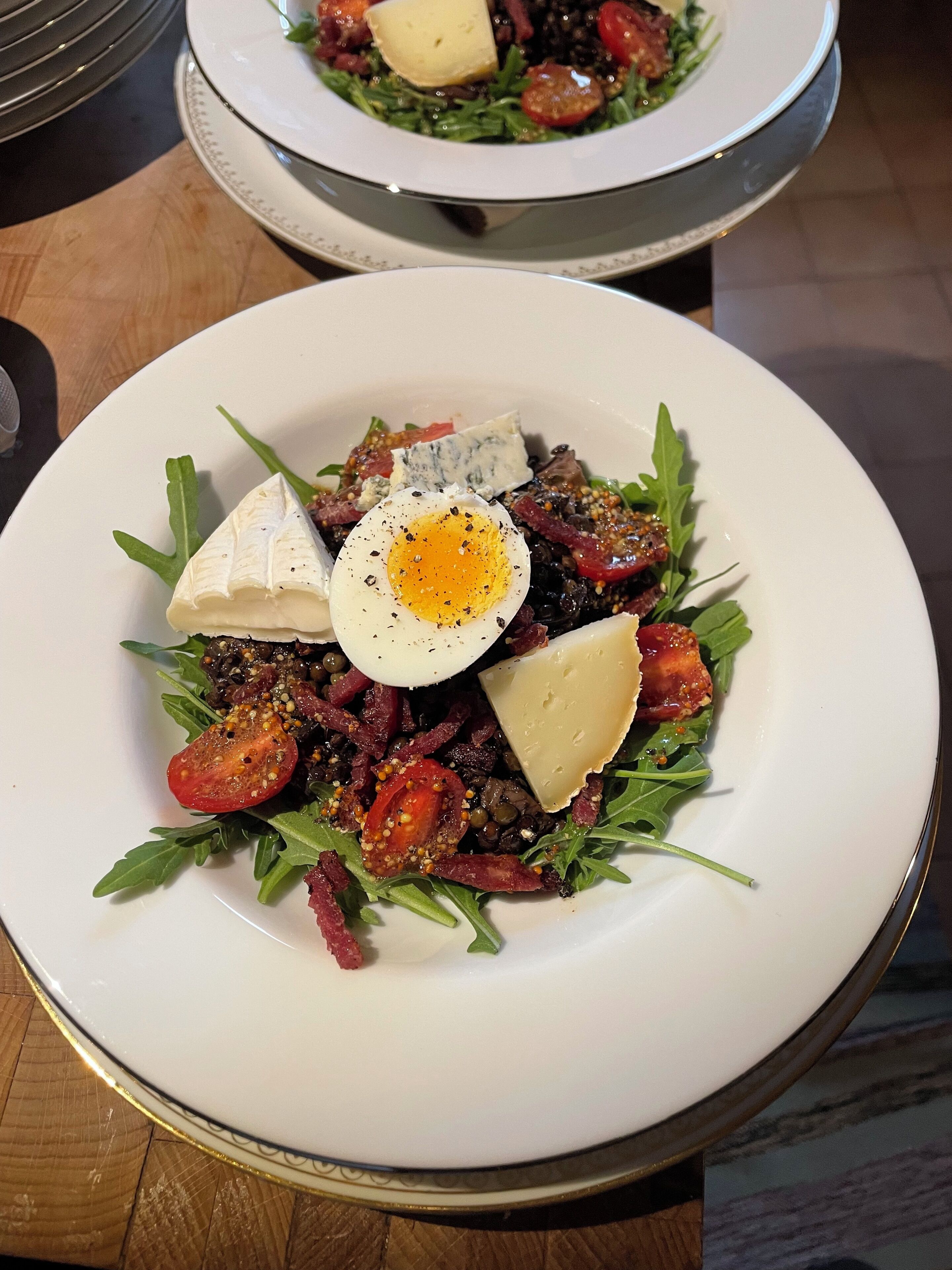 A plate of salad with arugula, cherry tomatoes, and a boiled egg.