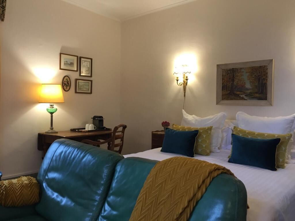 Et hotelværelse med seng, skrivebord, stol og lampe.