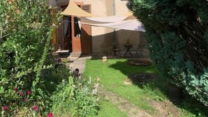 Een huis met een tuin, een houten deur en een overdekt terras.