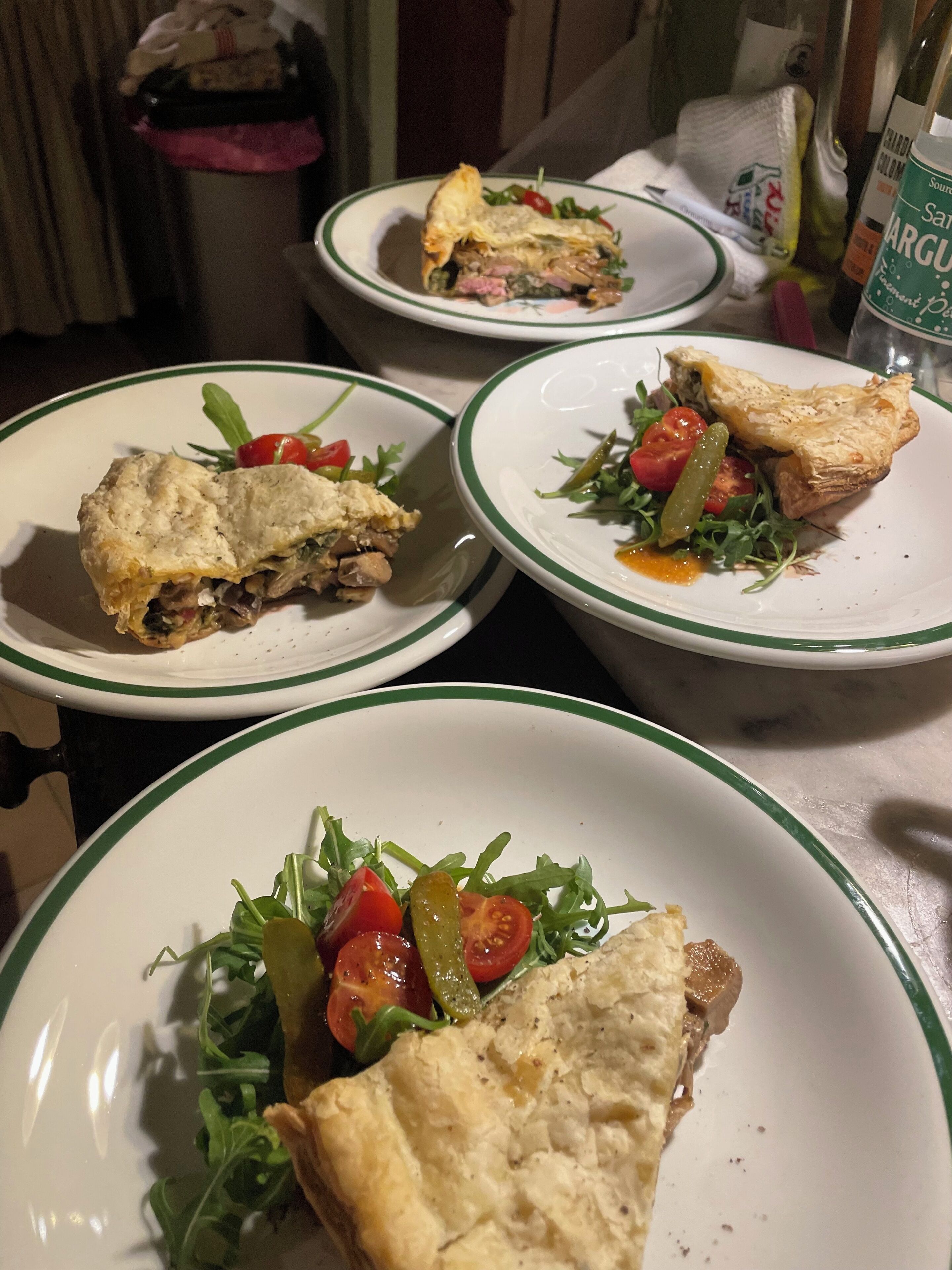 Une table à manger avec des assiettes remplies de nourriture, notamment une tarte et une salade.