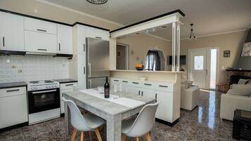 A modern kitchen with white cabinets, a granite countertop, and a dining area with a table and chairs.