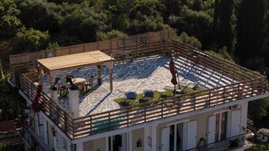 Eine Dachterrasse mit Holzboden, Sitzgelegenheiten im Freien und Blick auf den umliegenden Wald.