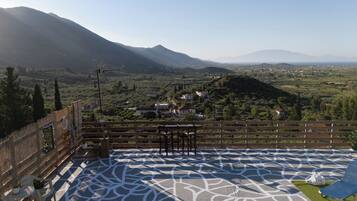A terrace with a patterned floor, a wooden fence, and a view of a town and mountains.