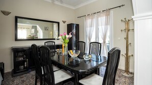 A dining room with a black table, six chairs, a vase with flowers, and a large mirror on the wall. - Ionian View Village House (Zakynthos)