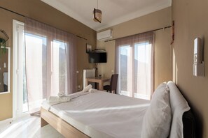 Ein Schlafzimmer mit einem Bett, einem Schreibtisch, einem Stuhl, einem Fernseher und einer Klimaanlage.