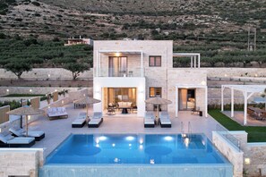 A modern two-story building with a swimming pool, outdoor seating, and a view of a hilly landscape. - Free heated pools & 800m sea (Kissamos)