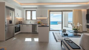 A modern kitchen with a central island, a dining area with a sofa, and a view of the ocean. - Actea Seaview Villas | Free* heated pools & 800m sea (Kissamos)