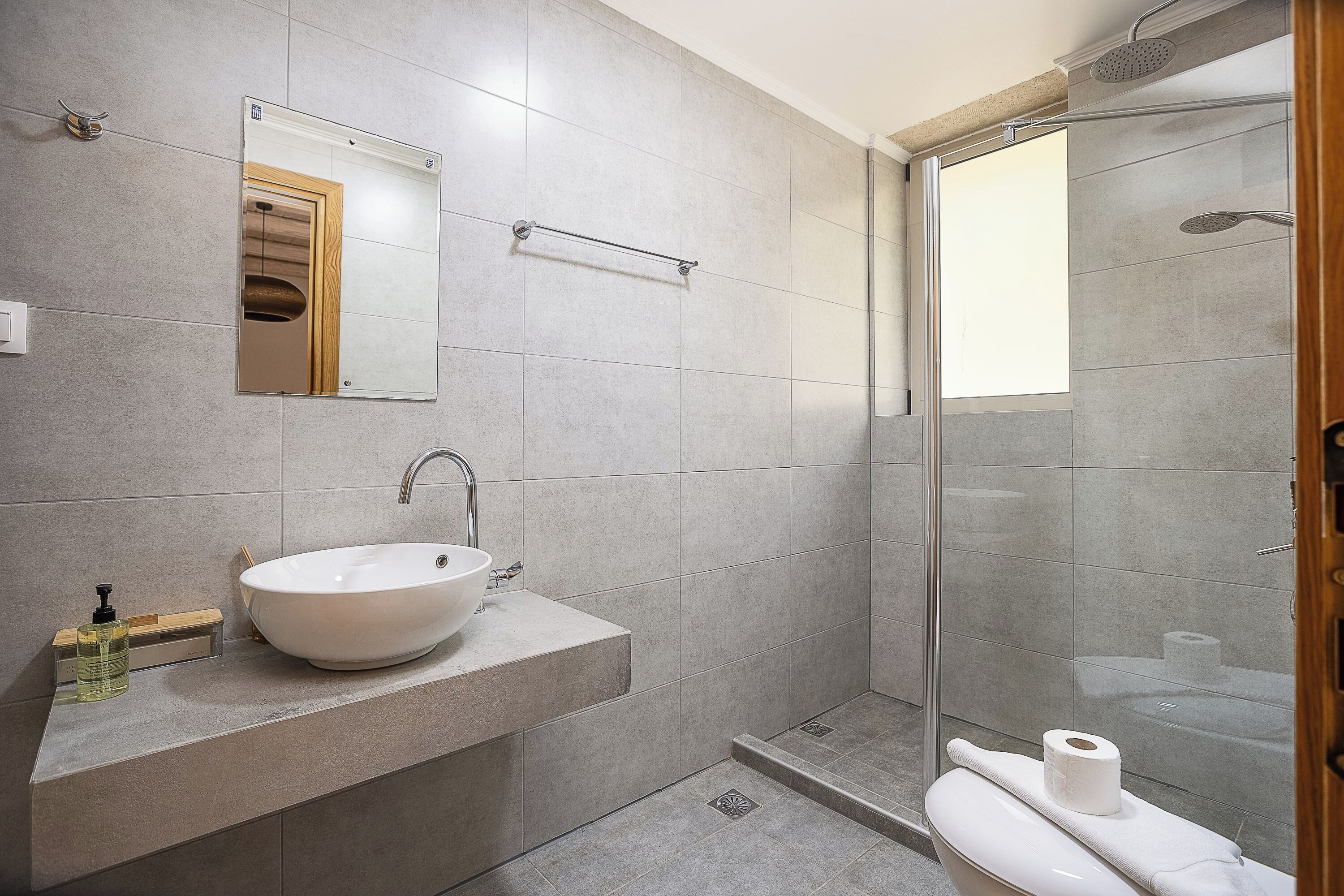 A modern bathroom with a large sink, mirror, and shower.