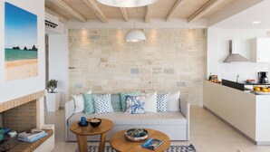 Ein modernes Wohnzimmer mit Steinwand, einer Couch mit gemusterten Kissen, einem Holztisch und einer hängenden Leuchte.