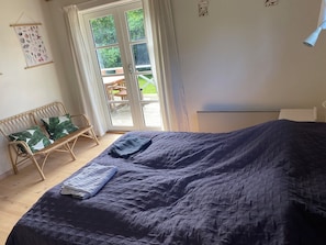 Een slaapkamer met een bed, een bankje en uitzicht door een glazen deur.