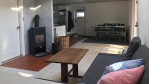 A cozy living area with a sofa, a small table, a fireplace, and a kitchen in the background. - Lovely holiday home near Vejby Strand (Vejby)