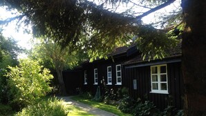 A wooden building with a pathway leading to it, surrounded by greenery. - Lovely holiday home near Vejby Strand (Vejby)