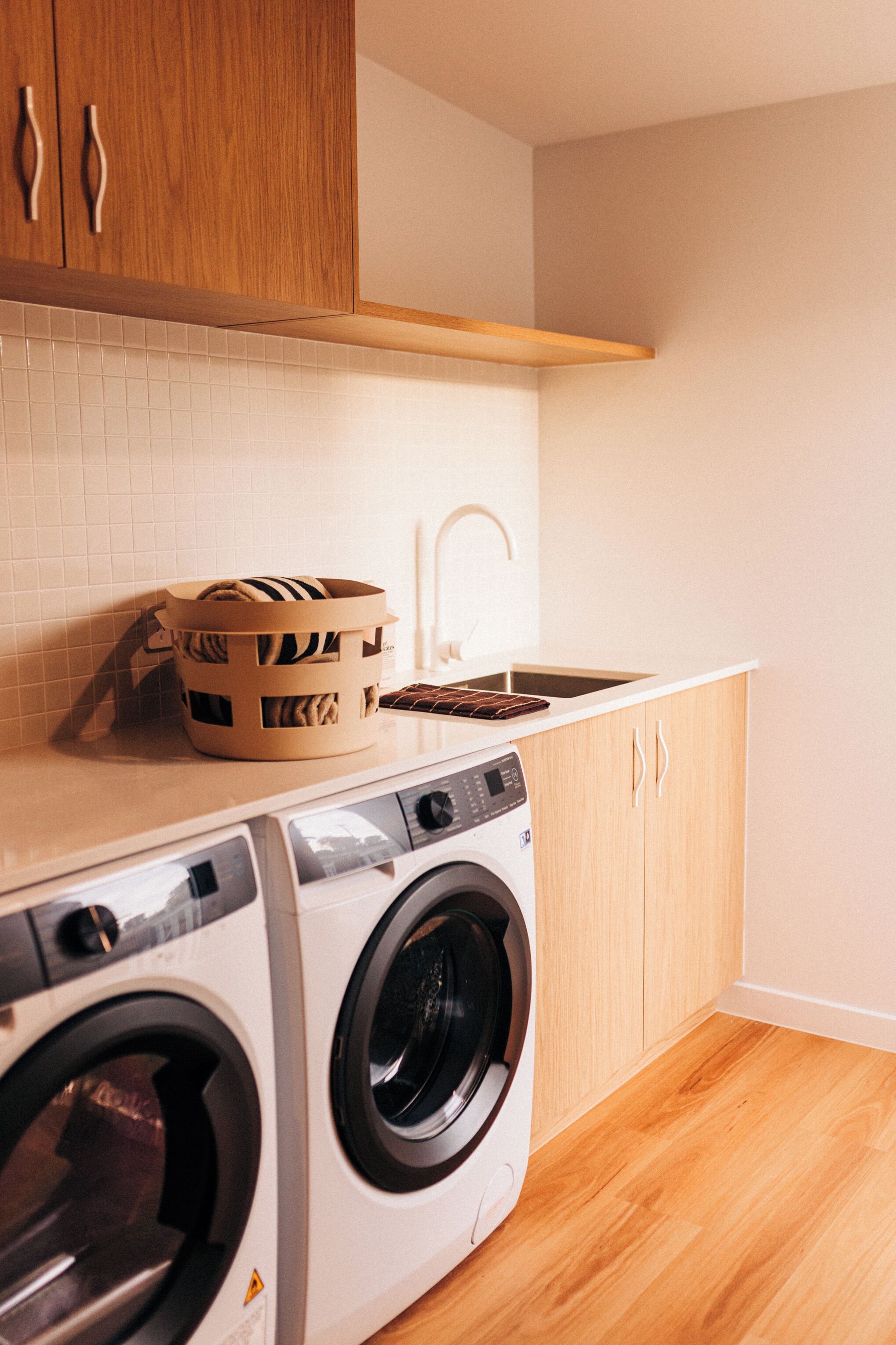 A compact laundry area with a washing machine, a drying rack, and a sink.