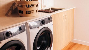 Un espacio pequeño para lavandería, con lavadora, tendedero y lavabo.