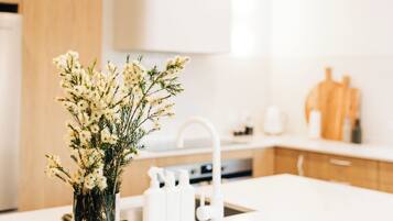 A modern kitchen with white cabinets, a white countertop, and a vase with flowers.