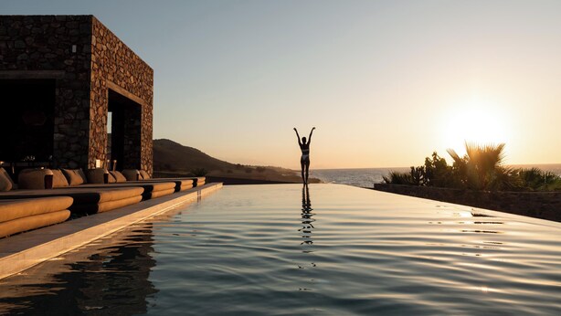 A poolside view with a stone building and a person standing in the water. - Ormus Villa - An Earthy Beachfront Sanctuary by etouri (Rethymno)