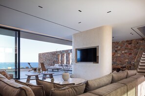 Relax in a serene ocean-view space with a curved sofa and flat-screen TV.