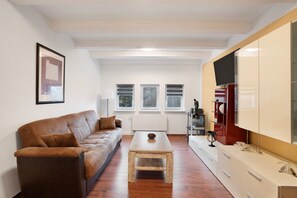 A modern living room with a brown leather sofa, a wooden coffee table, and a white cabinet with drawers.