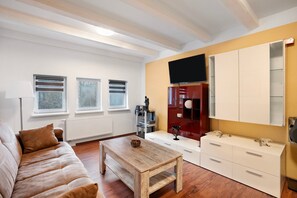 A living room with a sofa, a coffee table, a TV, and a cabinet.