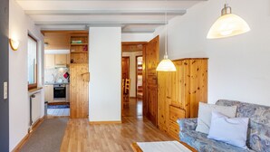A modern kitchen with wooden cabinets, a dining area with a sofa and a table, and a hallway leading to other rooms. - Holiday Apartment 'Feldbergblick' with Mountain View, Private Terrace and Wi-Fi (Todtnau)