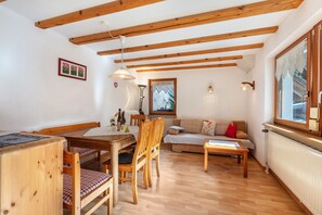 Une table à manger en bois avec des chaises, un canapé, une table basse et une fenêtre donnant sur un beau paysage.