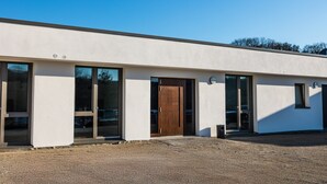 A modern building with large windows, a wooden door, and a gravel driveway. - Room '10' with Wi-Fi (Dußlingen)