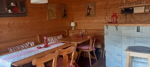A wooden interior with a dining table, chairs, a bench, a lamp, and a stone fireplace. - Country Apartment "Alte Mühle" Near Biggesee (Drolshagen-Berlinghausen)