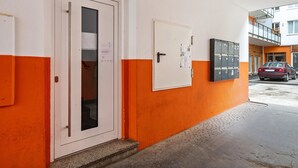 A hallway with a white door, a bulletin board, and a row of lockers. - Aldars Urban Trio Suite No. 9 with Wi-Fi and Air Conditioning (München)