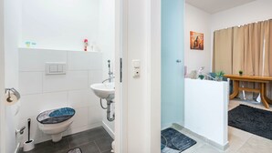 A bathroom with a toilet, sink, and shower area. - Aldars Urban Trio Suite No. 9 with Wi-Fi and Air Conditioning (München)