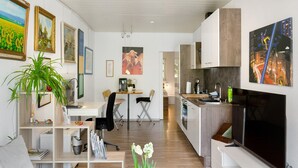 A modern kitchen with a dining area, a TV, and artwork on the walls.