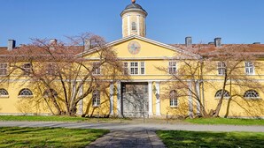A yellow building with a clock tower, arched windows, and a central door.