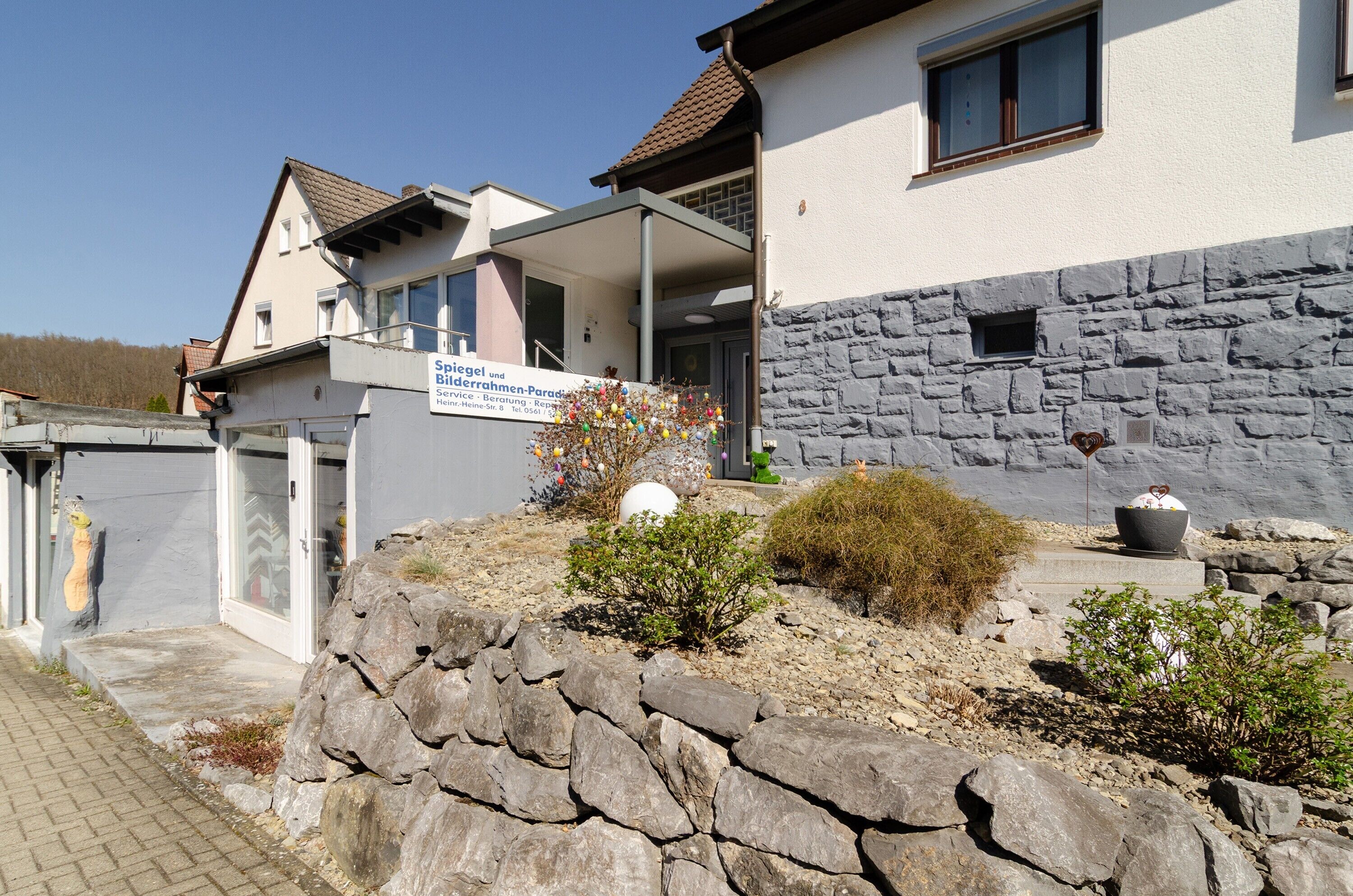 A building with a stone facade, a signboard, and a small garden area with rocks and plants.