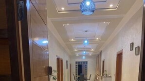 Een hotelgang met tapijt in rood, houten deuren en inbouwverlichting.